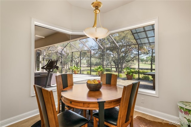 dining area with baseboards, wood finished floors, and a sunroom