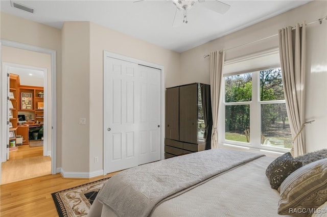 bedroom with visible vents, ceiling fan, baseboards, wood finished floors, and a closet