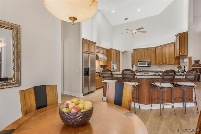 kitchen featuring a ceiling fan, under cabinet range hood, stainless steel appliances, a peninsula, and light wood finished floors