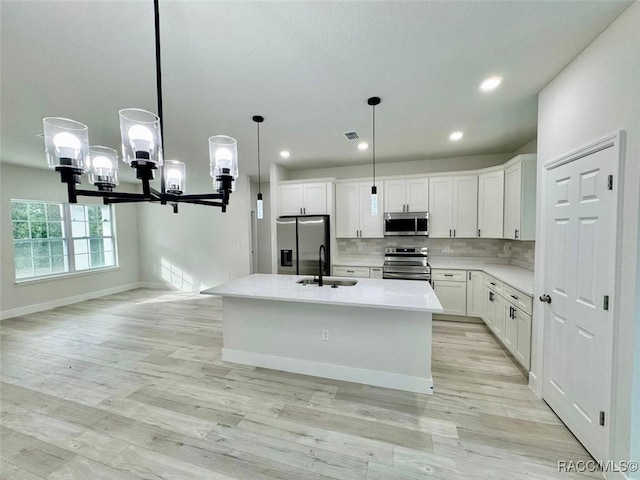 kitchen with sink, stainless steel appliances, an island with sink, decorative light fixtures, and white cabinets