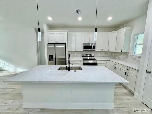 kitchen featuring decorative light fixtures, stainless steel appliances, light stone counters, and sink