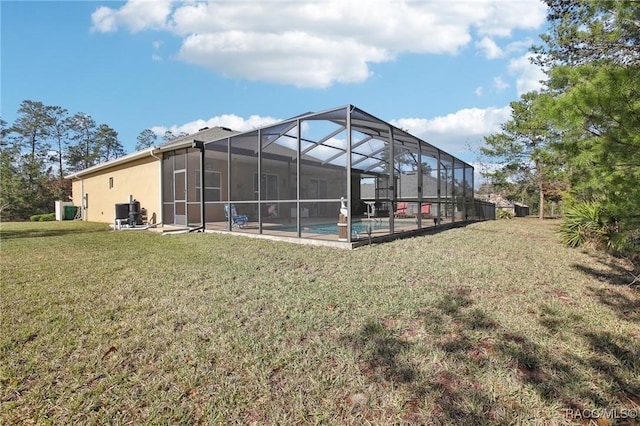 rear view of house featuring a yard and glass enclosure