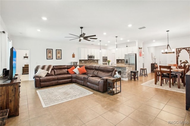 tiled living room featuring ornamental molding and ceiling fan with notable chandelier