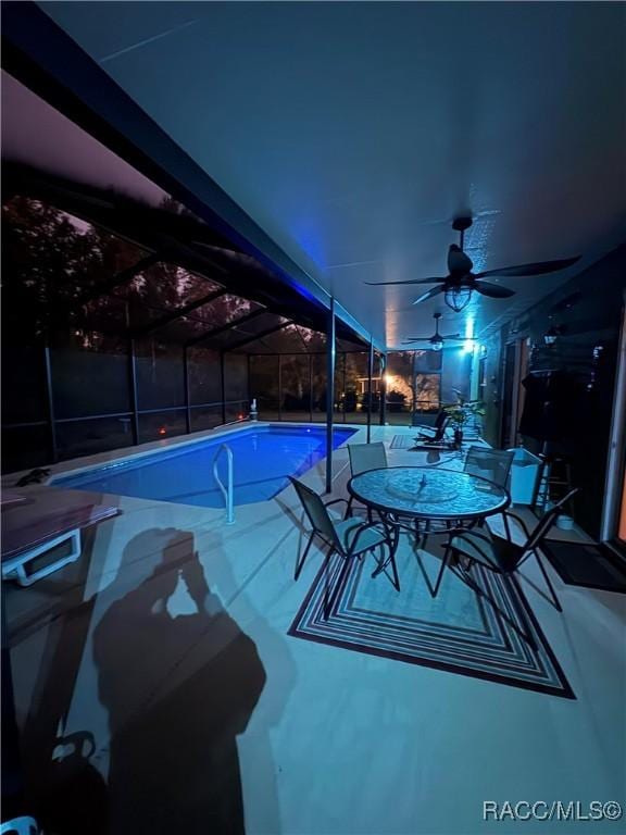 view of swimming pool featuring ceiling fan and glass enclosure