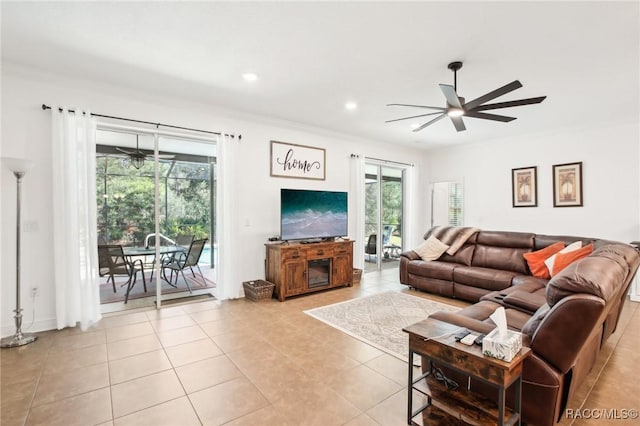 living room featuring ornamental molding, light tile patterned floors, and ceiling fan