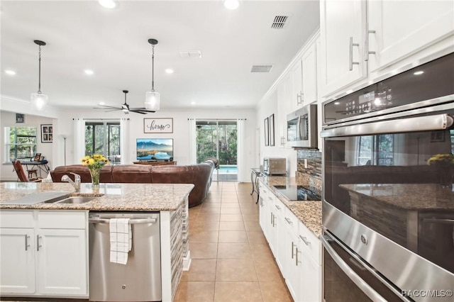 kitchen featuring appliances with stainless steel finishes, hanging light fixtures, and white cabinets