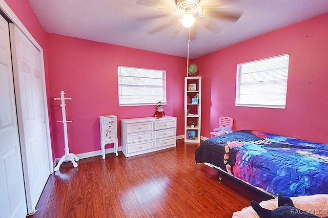 bedroom with multiple windows, a closet, dark hardwood / wood-style floors, and ceiling fan