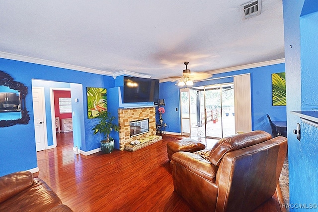 living room with a stone fireplace, ceiling fan, ornamental molding, and hardwood / wood-style flooring