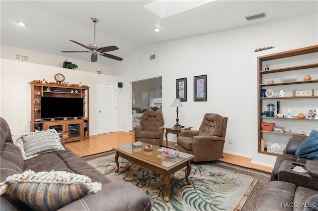 living room featuring vaulted ceiling with skylight, ceiling fan, and hardwood / wood-style floors