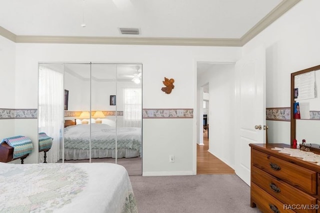 carpeted bedroom featuring ceiling fan, ornamental molding, and a closet