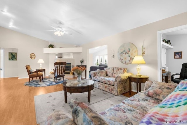 living room with a tile fireplace, ceiling fan, light hardwood / wood-style floors, and lofted ceiling