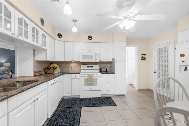 kitchen featuring backsplash, white appliances, light tile patterned floors, dark stone countertops, and white cabinets