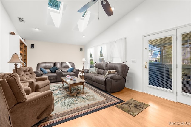 living room featuring a skylight, ceiling fan, high vaulted ceiling, and wood-type flooring