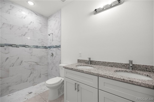 bathroom featuring vanity, toilet, and a tile shower