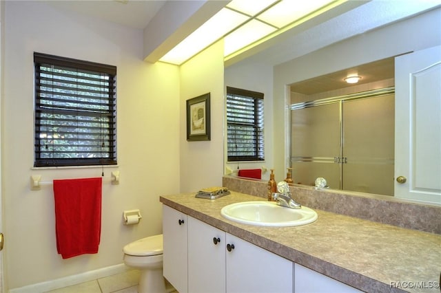 bathroom featuring tile patterned flooring, vanity, toilet, and a shower with shower door