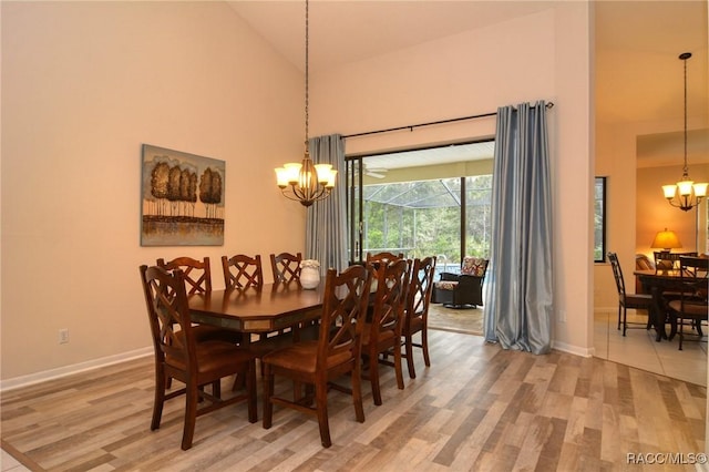 dining area with a notable chandelier, wood-type flooring, and high vaulted ceiling