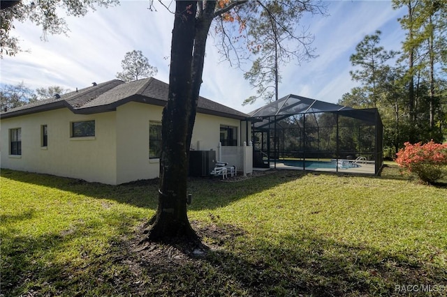 exterior space featuring a lanai, a yard, and central air condition unit