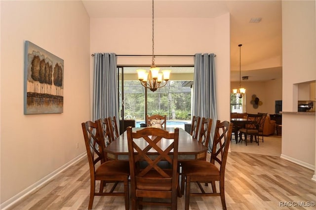 dining room featuring hardwood / wood-style floors, a towering ceiling, and a notable chandelier