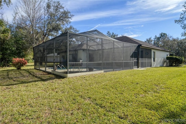 rear view of house with a yard and glass enclosure