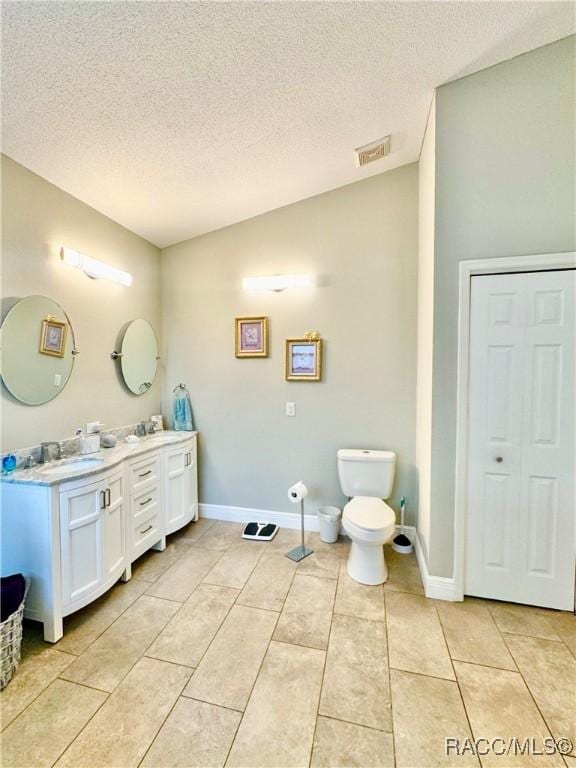 bathroom with a textured ceiling, tile patterned floors, vanity, and toilet