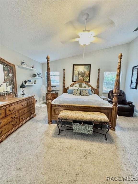 bedroom with ceiling fan, light colored carpet, vaulted ceiling, and a textured ceiling