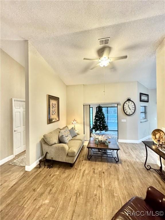 living room featuring a textured ceiling, ceiling fan, vaulted ceiling, and light hardwood / wood-style flooring