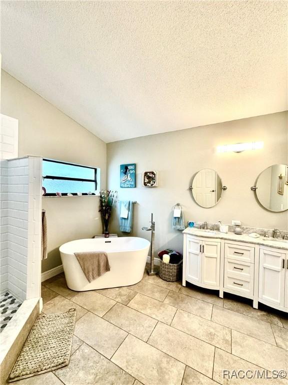 bathroom with separate shower and tub, vanity, vaulted ceiling, and a textured ceiling