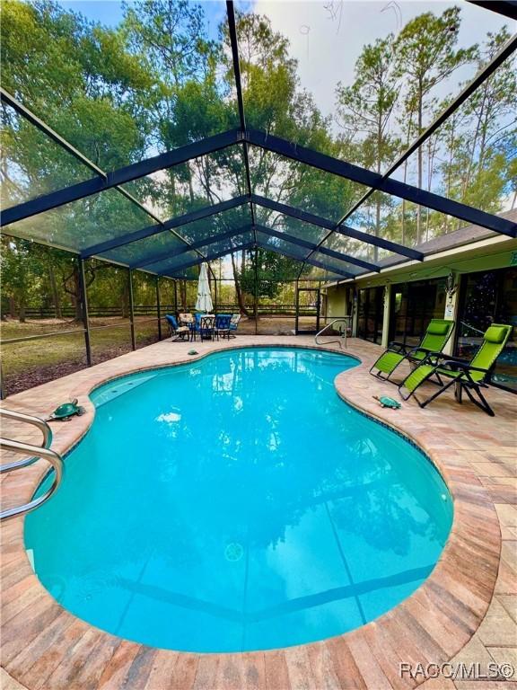 view of pool with a patio area and glass enclosure