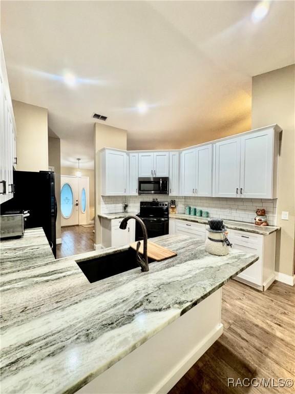 kitchen featuring light stone countertops, sink, white cabinetry, and black appliances