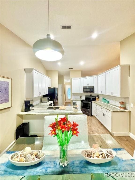 kitchen featuring white cabinets, appliances with stainless steel finishes, sink, kitchen peninsula, and light hardwood / wood-style flooring