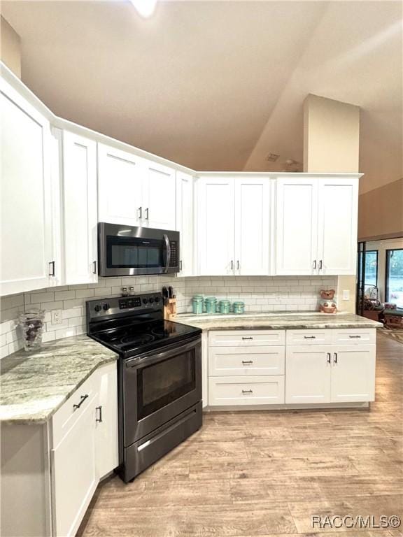 kitchen with lofted ceiling, black range with electric stovetop, backsplash, and white cabinetry