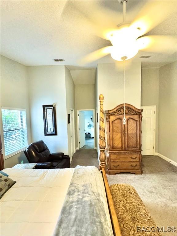 carpeted bedroom featuring ceiling fan, a high ceiling, and a textured ceiling