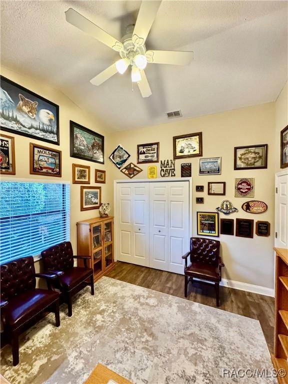 living area featuring ceiling fan and dark hardwood / wood-style floors