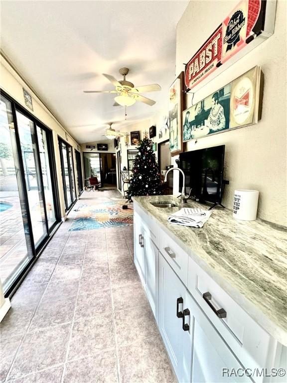 kitchen with ceiling fan, sink, white cabinetry, and plenty of natural light