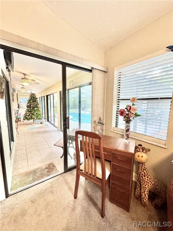 dining room with ceiling fan, vaulted ceiling, and light carpet