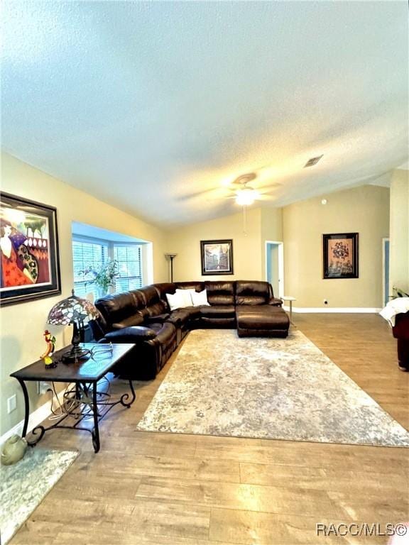 living room with lofted ceiling, light wood-type flooring, a textured ceiling, and ceiling fan