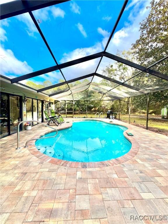 view of swimming pool featuring a lanai and a patio