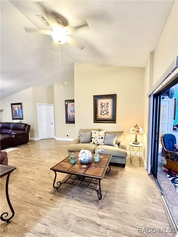 living room featuring light hardwood / wood-style floors, a textured ceiling, lofted ceiling, and ceiling fan