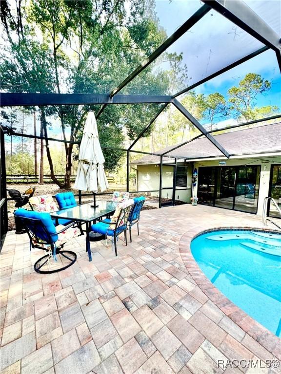 view of pool with glass enclosure and a patio area