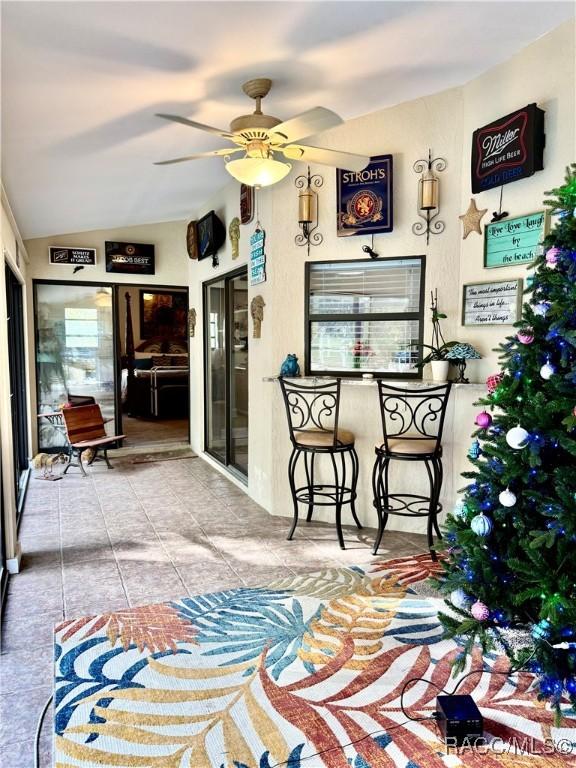 interior space with ceiling fan, vaulted ceiling, and light tile patterned flooring