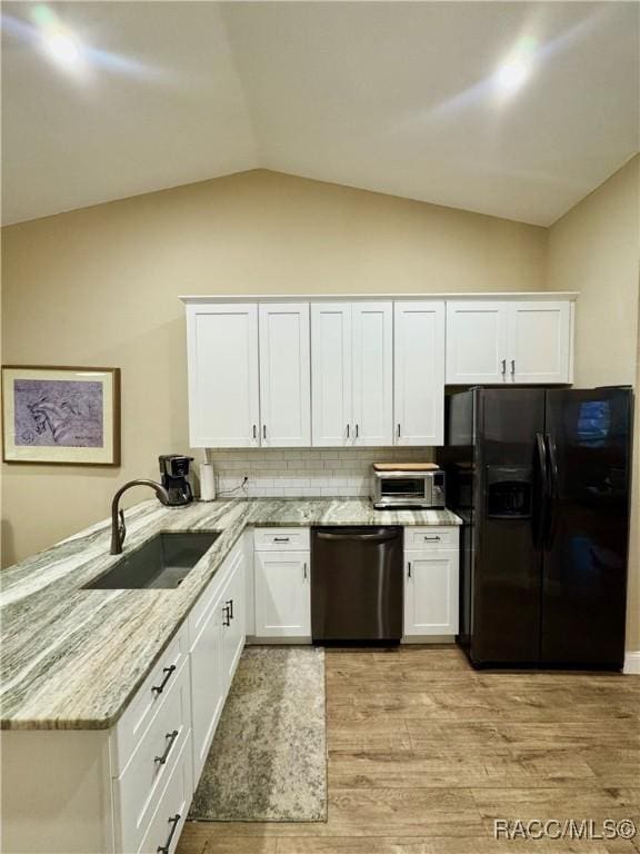 kitchen with dishwashing machine, white cabinets, tasteful backsplash, sink, and black fridge