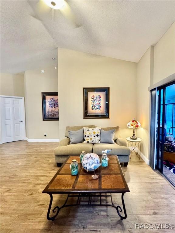 living room with ceiling fan, high vaulted ceiling, and light hardwood / wood-style floors