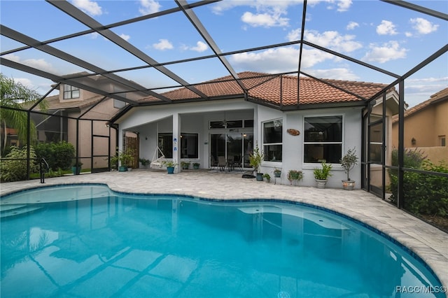 rear view of property featuring glass enclosure, ceiling fan, and a patio area