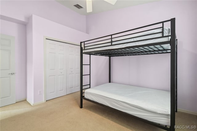 bedroom with ceiling fan, a closet, and light colored carpet