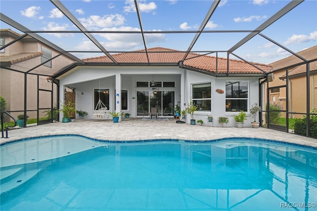 view of swimming pool featuring glass enclosure, ceiling fan, and a patio area