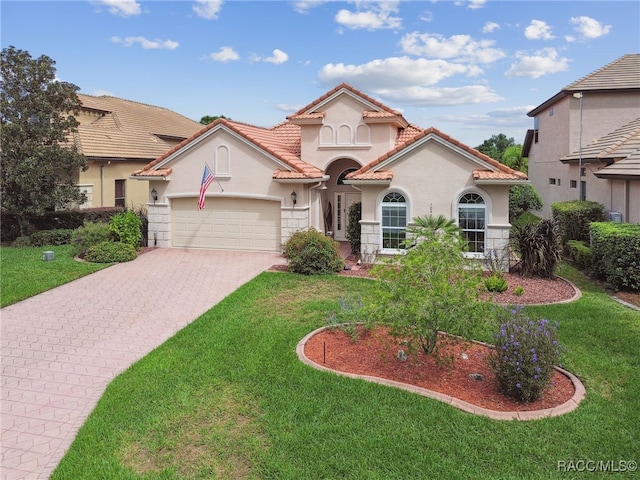 mediterranean / spanish-style home with a garage and a front lawn