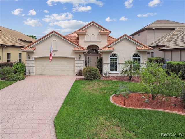 mediterranean / spanish home featuring a garage and a front lawn