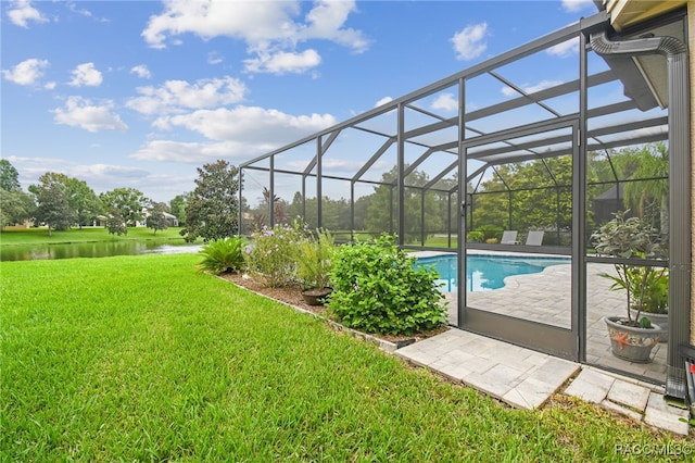 view of pool with a lawn, glass enclosure, a patio area, and a water view