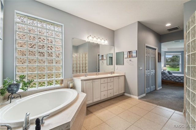 bathroom with tile patterned flooring, vanity, and tiled tub