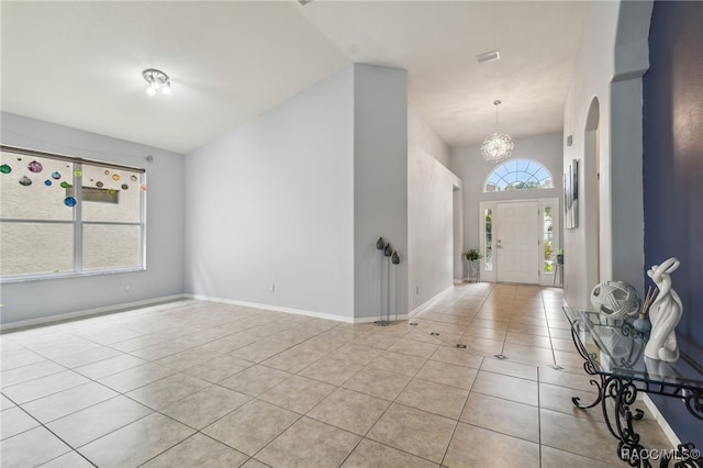 tiled foyer with vaulted ceiling, a wealth of natural light, and an inviting chandelier